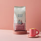 The Bear and the Beard coffee blend on a pink background with a pink bubble mug. Features rich dark chocolate, maple syrup & hazelnut praline flavours. $1 from every kilo of Bear and the Beard coffee sold goes directly to help Bear Cottage provide care for children with life-limiting conditions.