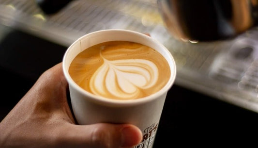 pouring latte into paper cup