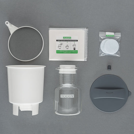 Collection of Toddy coffee brewing equipment on a gray background